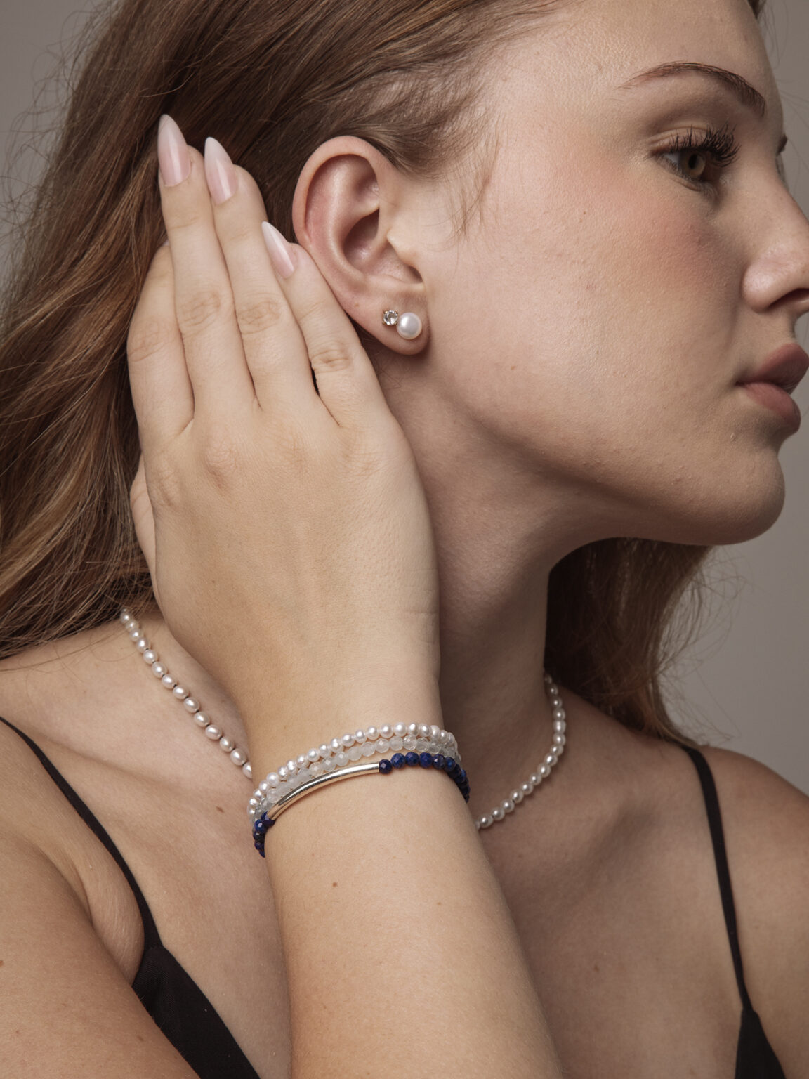 Triple-strand cultured pearl, aquamarine and lapis lazuli bracelet worn on a wrist